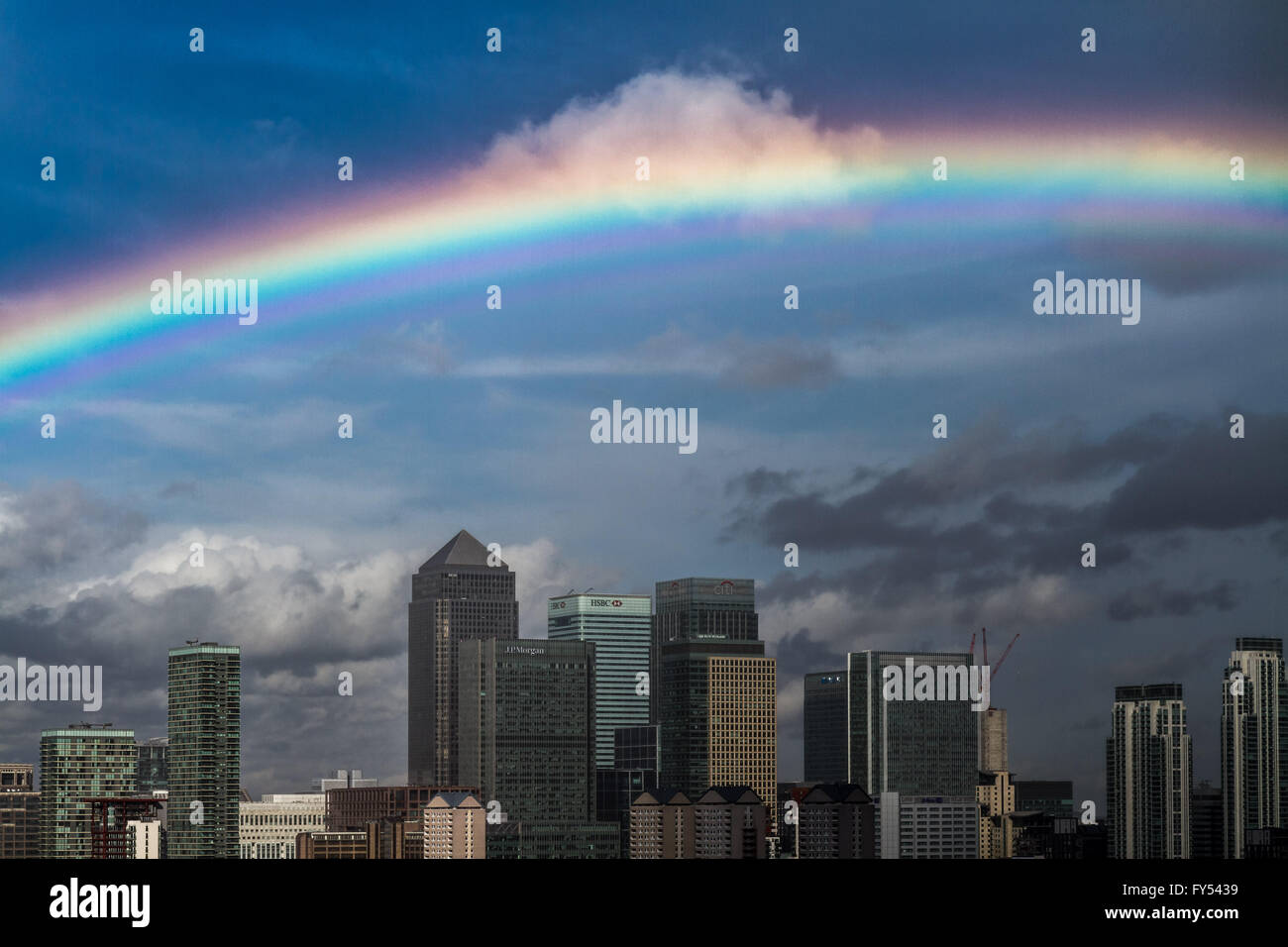 A massive colourful rainbow seen over south east London including Canary Wharf business park buildings Stock Photo
