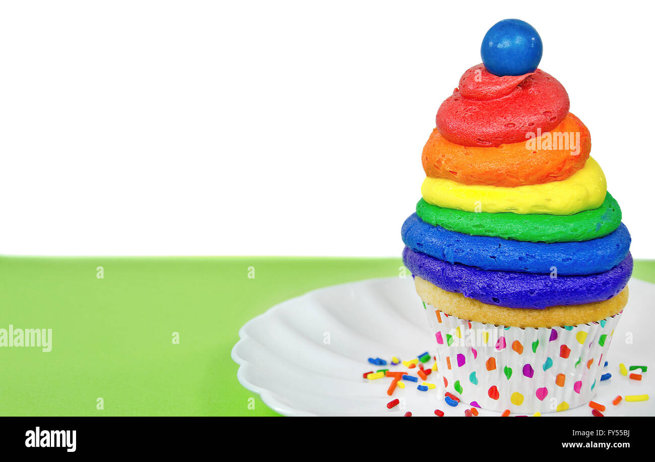 Rainbow frosting and blue gum ball on cupcake with colorful sprinkles. Stock Photo