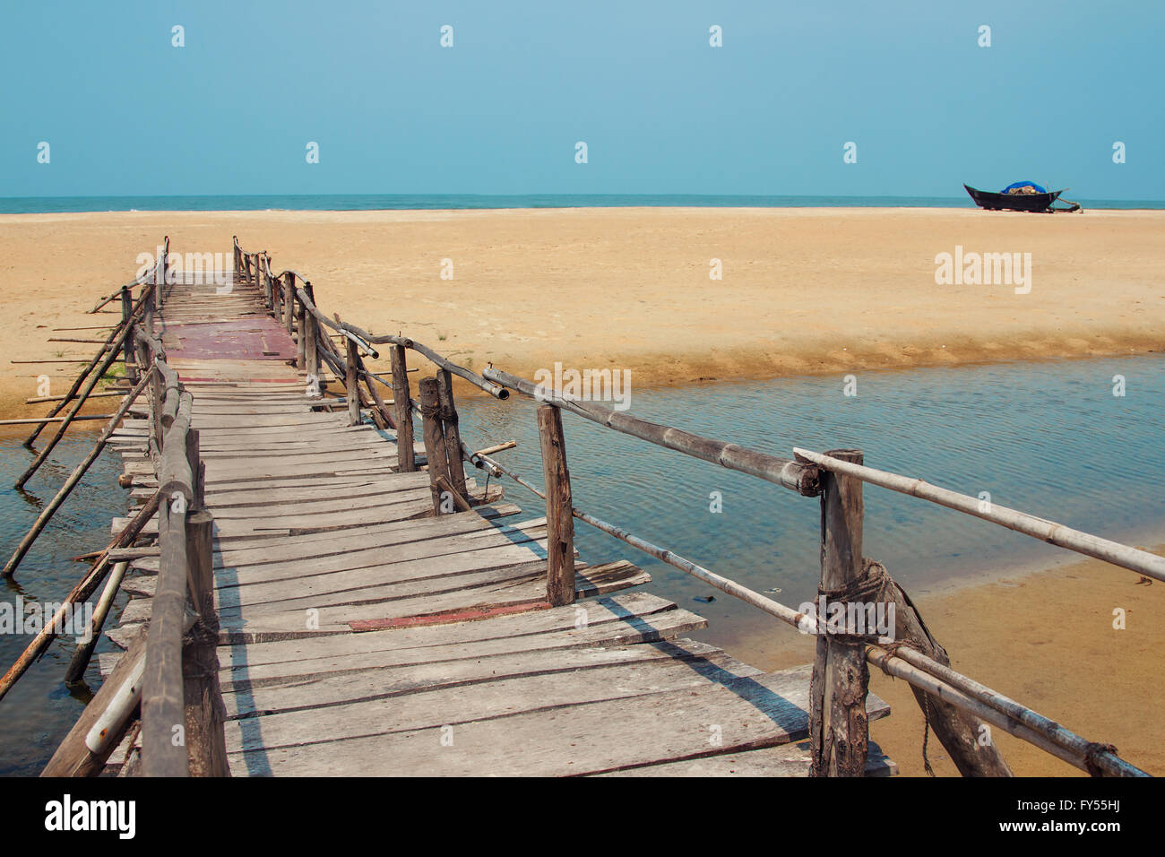 Creative travel photo with blue sky, sea, beach and wood plank road leading far away Stock Photo