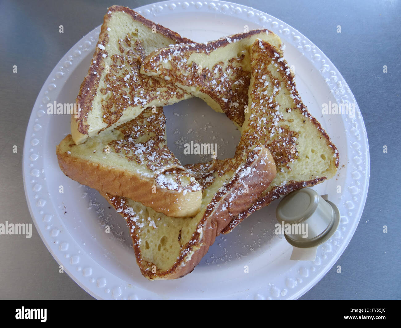 Sweet Bread French Toast - 5 Pieces with frosting and side of butter on a plastic plate. Stock Photo