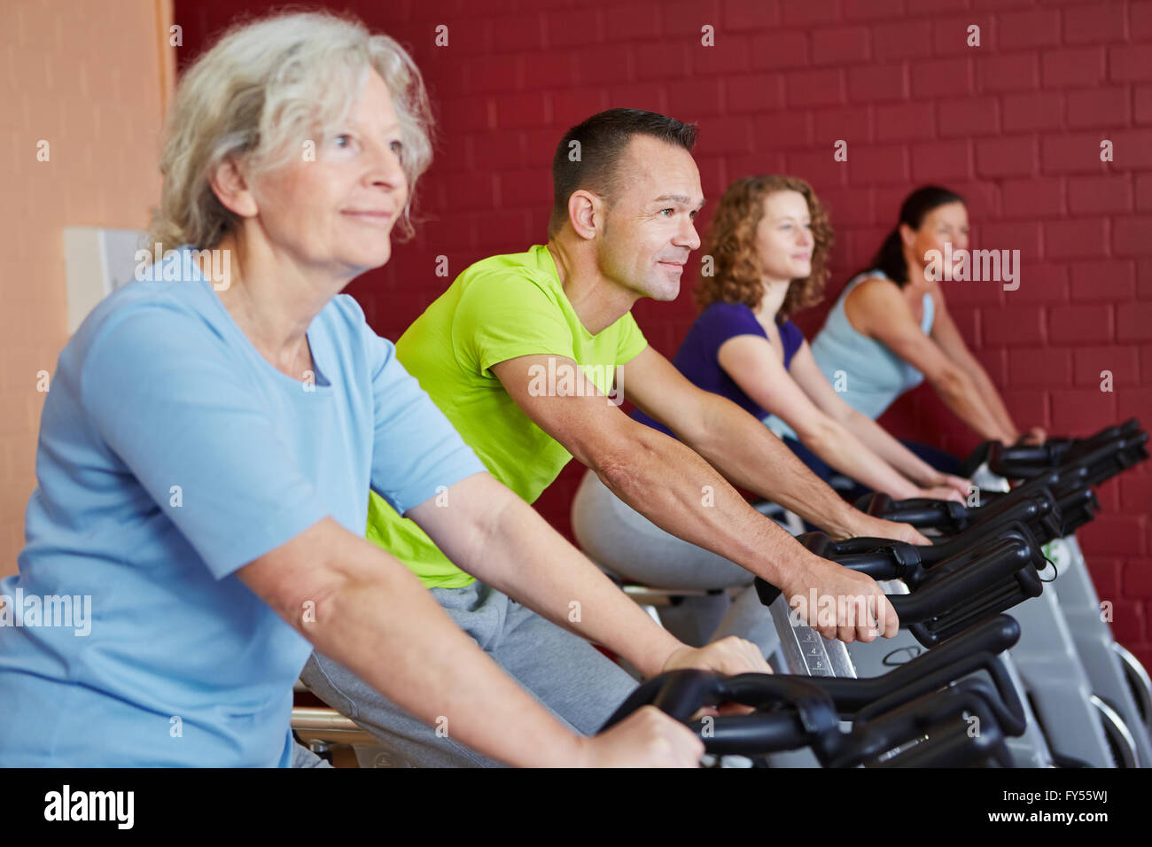 Group riding spinning bikes in a fitness class in health club Stock