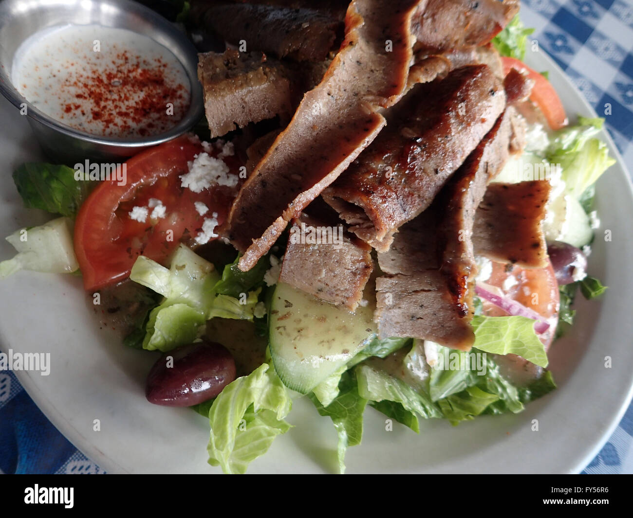 Gyros Salad - Hot slices of beef and lamb topped tzatziki sauce on a bed of romaine lettuce, onions, tomatoes, cucumbers, kalama Stock Photo