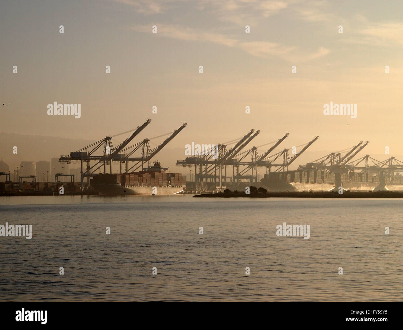 Cargo Boats for of crates rest under cranes in Oakland Harbor on a foggy day in California. Stock Photo