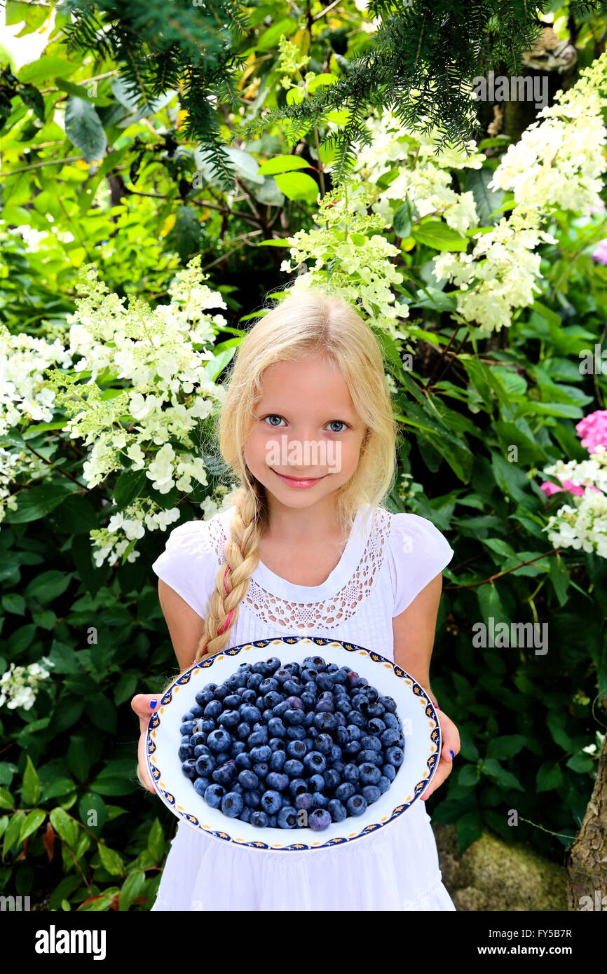 Girl offering blueberries in bowl Stock Photo