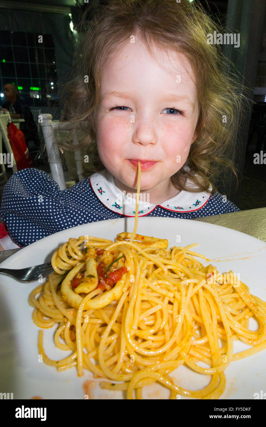 Young child girl kid / kids aged 3 -4 year old eating authentic genuine spaghetti in Italian pasta restaurant in Naples Italy Stock Photo