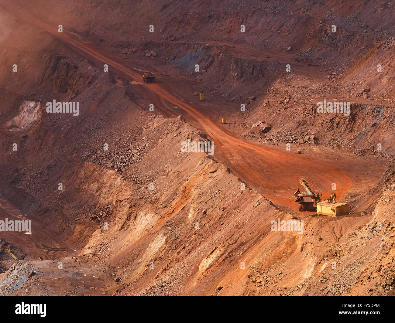 Top view of sunlit open-pit mine with quarry excavator loading iron ore to dump truck Stock Photo
