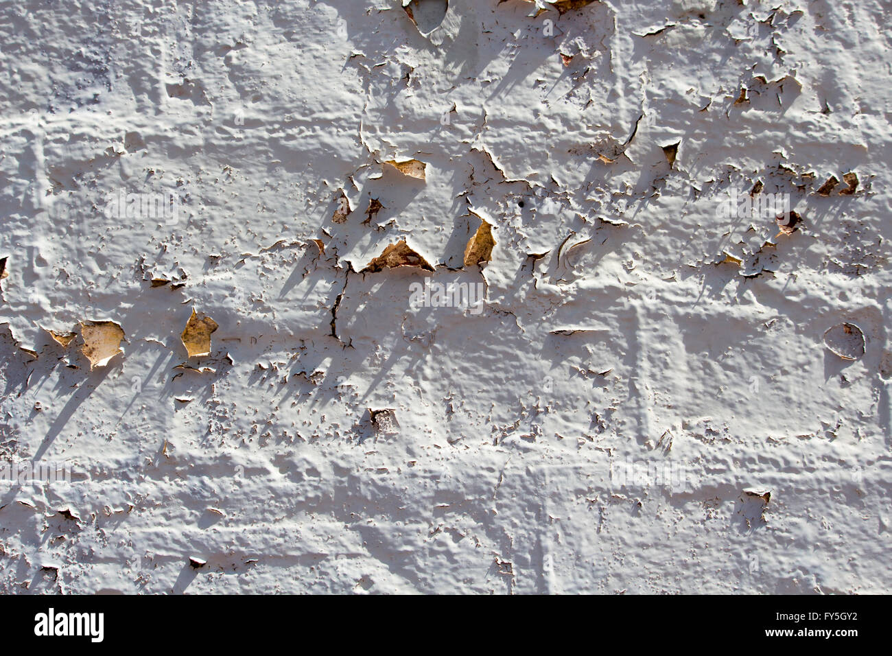 Weathered  eroded  peeling  grey painted  cement rendered  clay brick wall   exposed to the elements of wind and rain  is grungy Stock Photo