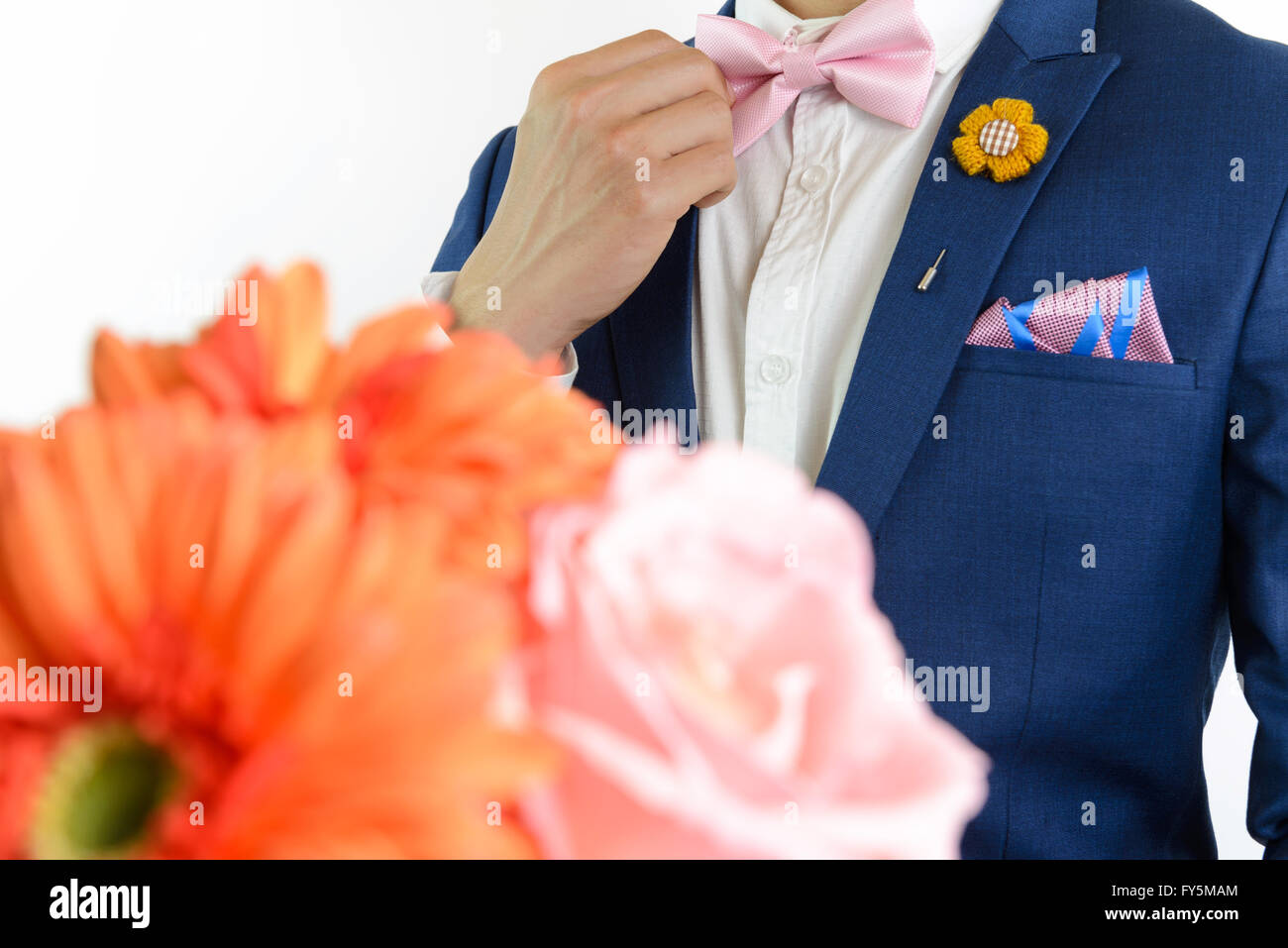 Man in blue suit with pink bow tie, flower brooch, and pink blue strip pocket square, close up, carry flowers Stock Photo