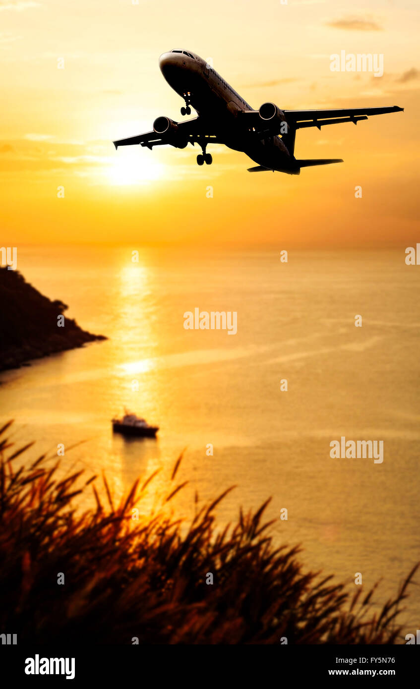 Airplane come down to the land on blurred sea sunset in twilight Stock Photo