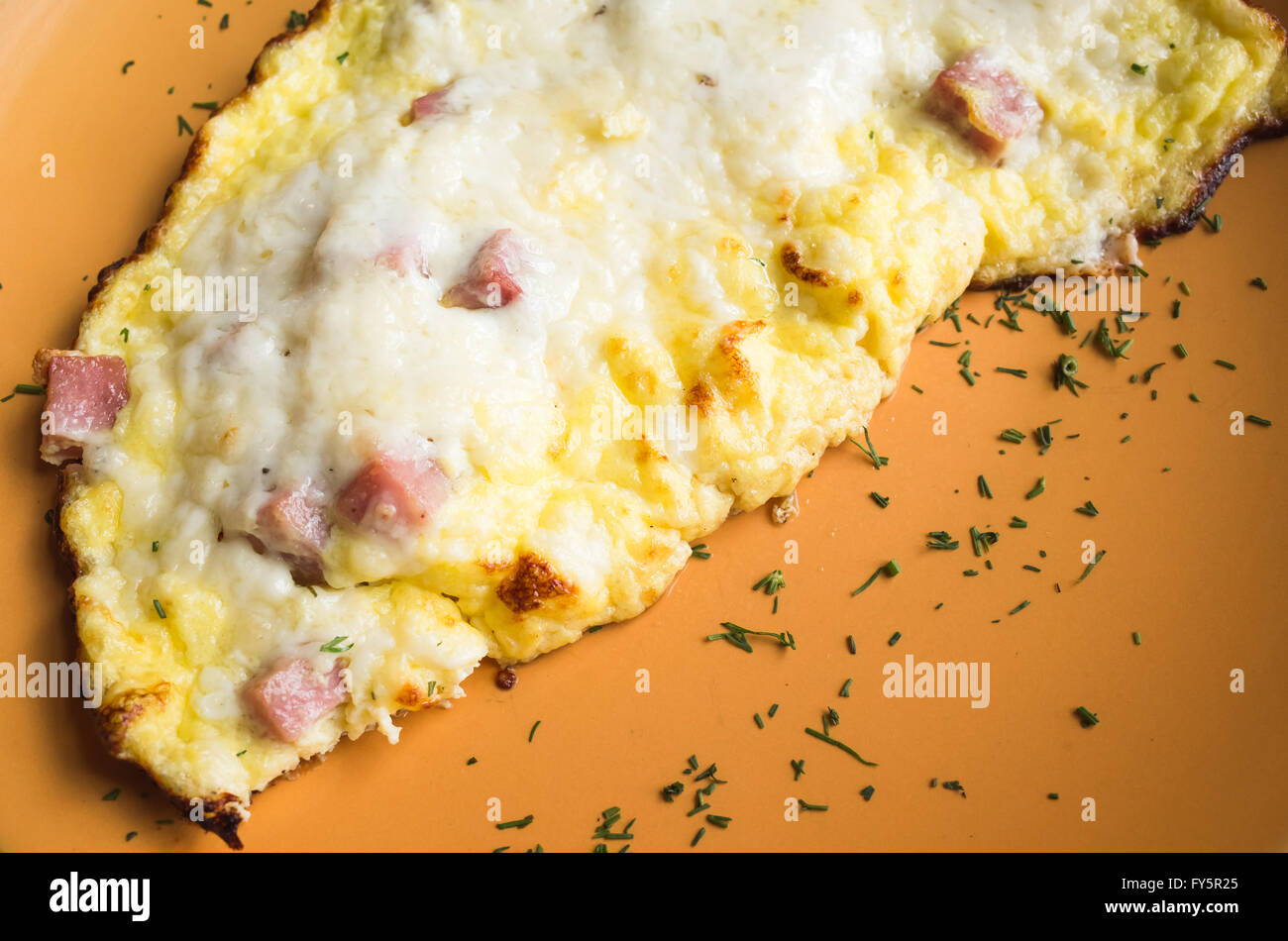 Freshly roasted omelet with ham and cheese on orange plate. Breakfast theme Stock Photo