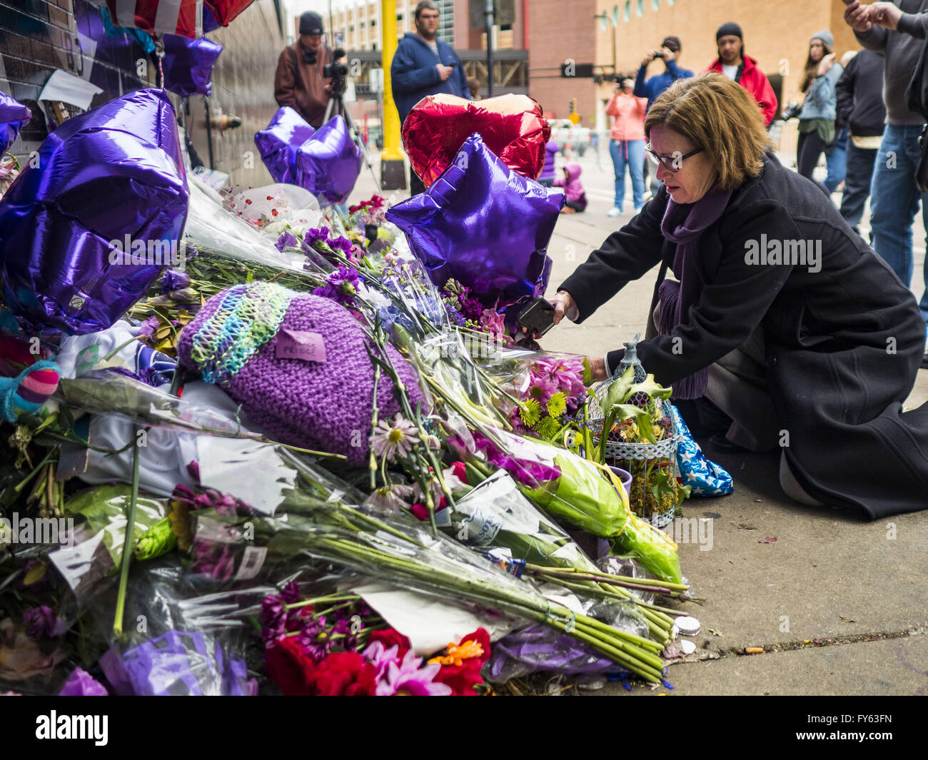 Minneapolis, MN, USA. 22nd Apr, 2016. A woman lays flowers at a memorial for Prince in front of 1st Ave in Minneapolis. Thousands of people came to 1st Ave in Minneapolis Friday, to mourn the death of Prince, whose full name is Prince Rogers Nelson. 1st Ave is the nightclub the musical icon made famous in his semi autobiographical movie ''Purple Rain.'' Prince, 57 years old, died Thursday, April 21, 2016, at Paisley Park, his home, office and recording complex in Chanhassen, MN. Credit:  Jack Kurtz/ZUMA Wire/Alamy Live News Stock Photo