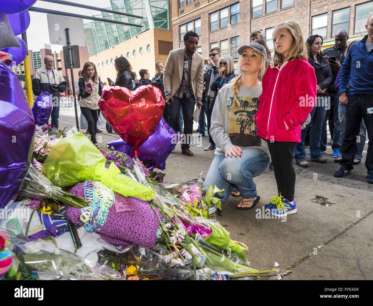 Minneapolis, MN, USA. 22nd Apr, 2016. A woman and her daughter look at a memorial for Prince at 1st Ave in Minneapolis. Thousands of people came to 1st Ave in Minneapolis Friday to mourn the death of Prince, whose full name is Prince Rogers Nelson. 1st Ave is the nightclub the musical icon made famous in his semi autobiographical movie ''Purple Rain.'' Prince, 57 years old, died Thursday, April 21, 2016, at Paisley Park, his home, office and recording complex in Chanhassen, MN. Credit:  Jack Kurtz/ZUMA Wire/Alamy Live News Stock Photo