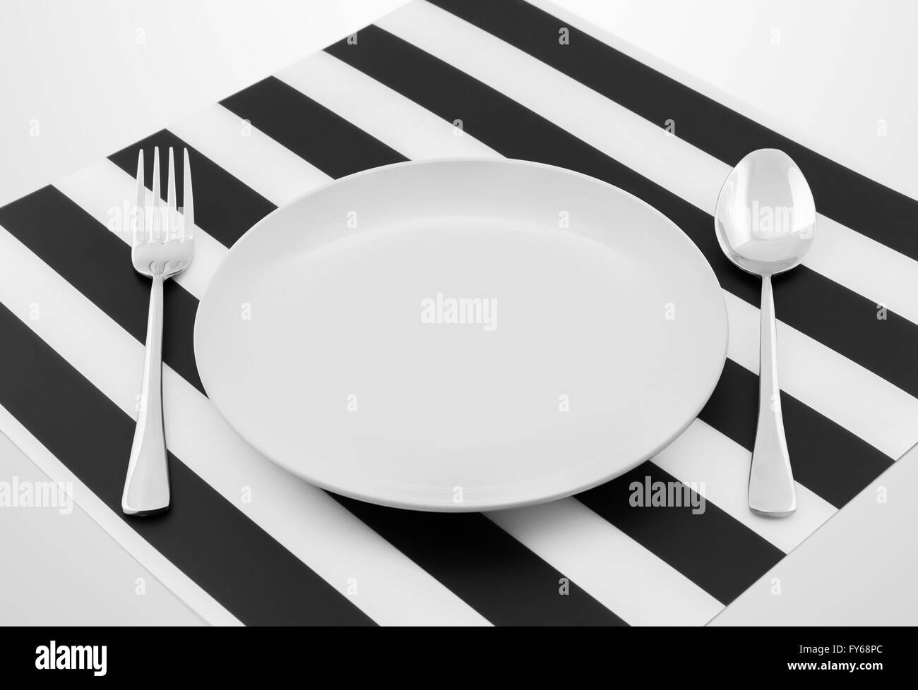 Plate with spoon and fork on a table Stock Photo