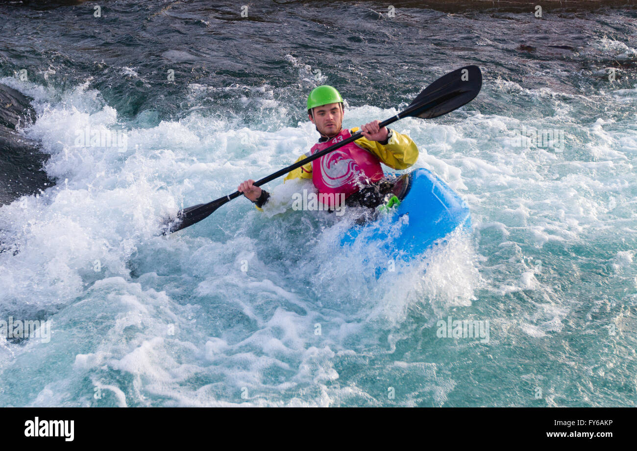 Young male man paddling a kayak in white water.  The man is in some rough rapids holding onto the paddle. Stock Photo