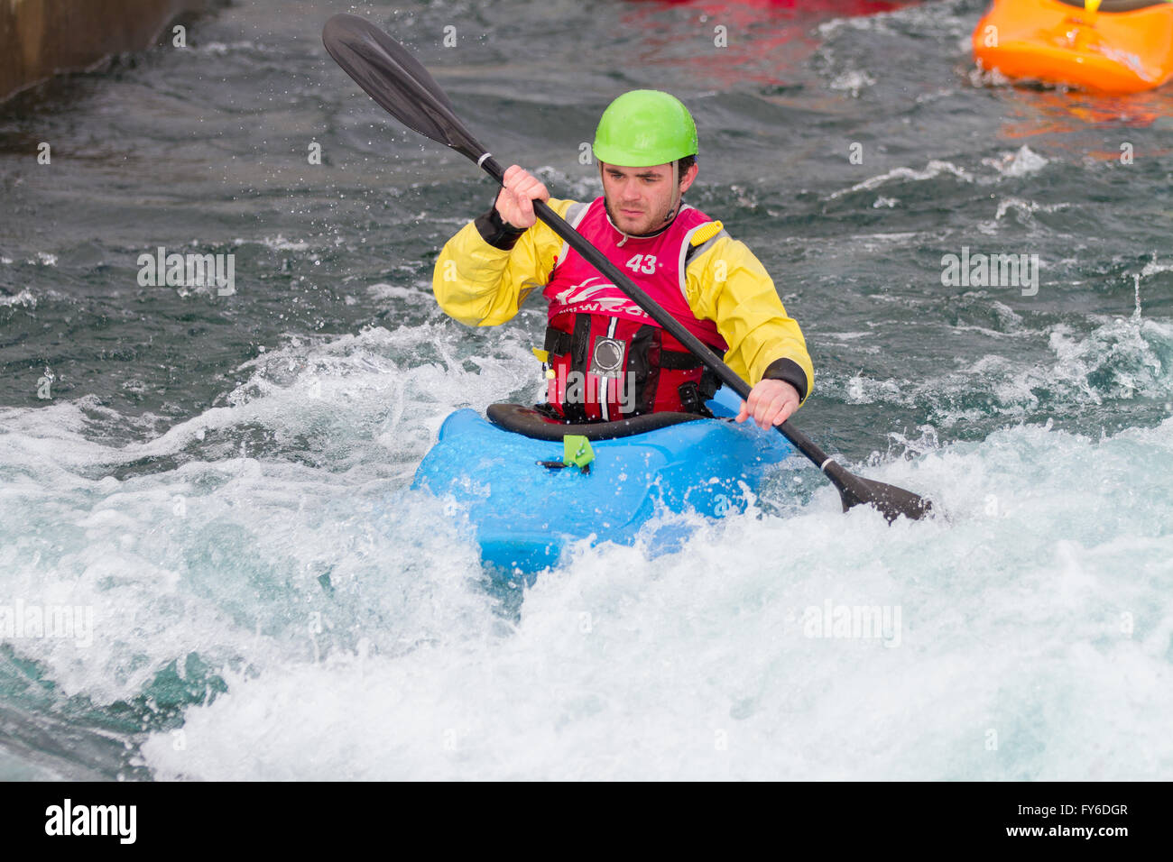 Young male man paddling a kayak in white water.  The man is paddling upstream towards the rapids and camera. Stock Photo