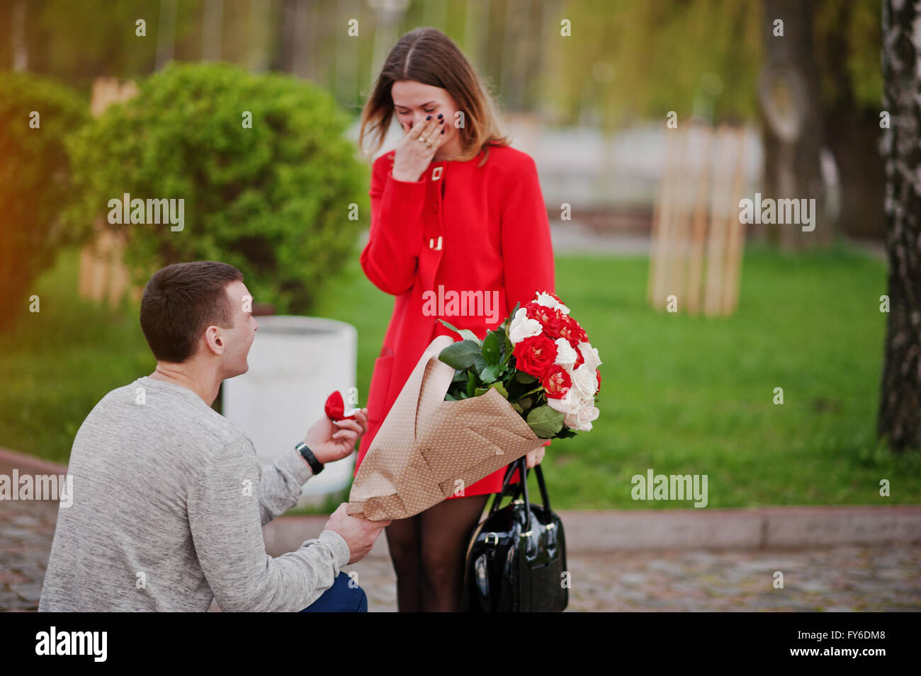 Marriage proposal. Man with boquet of flowers kneeling and give