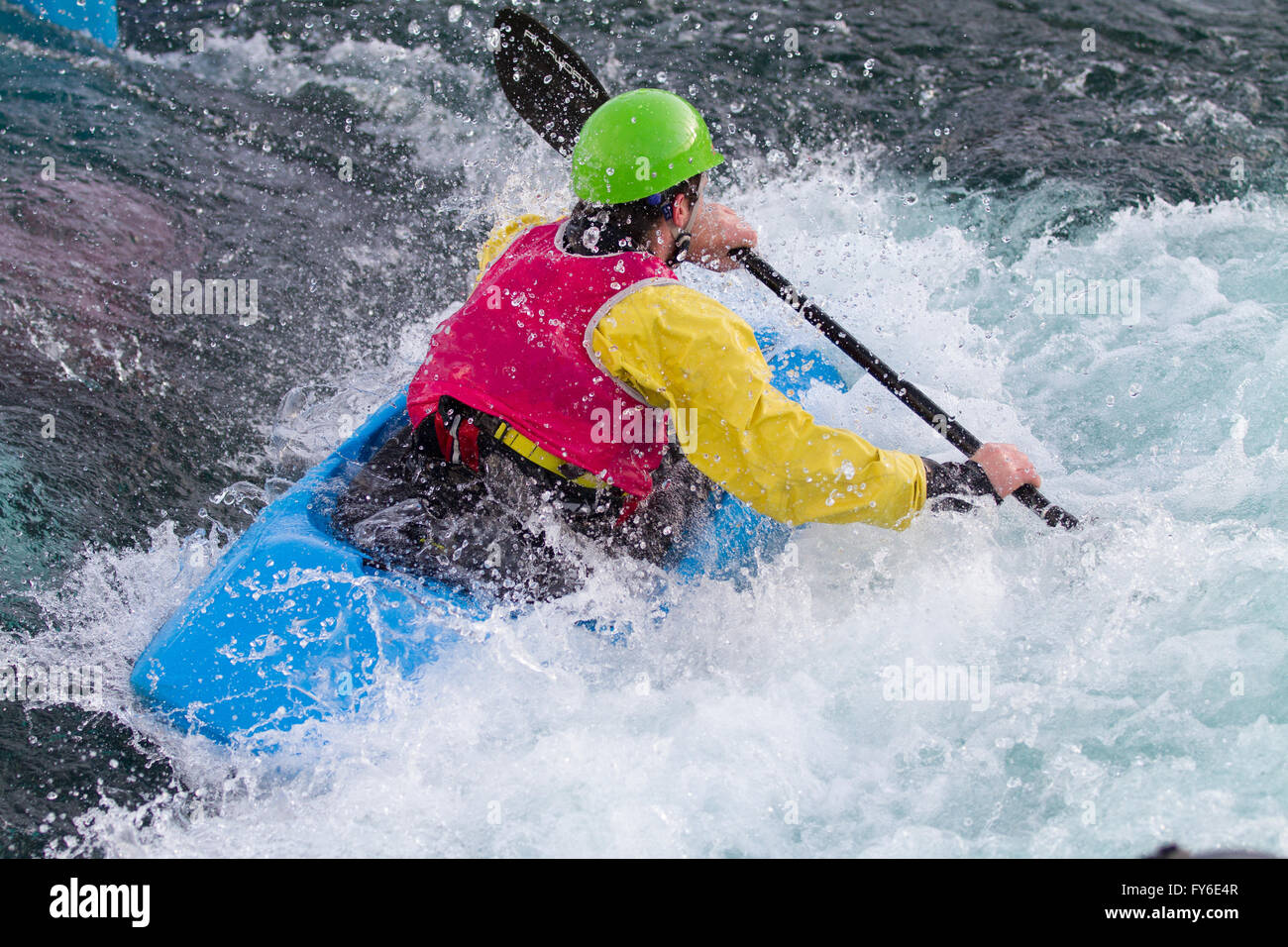 Young male man paddling kayak in white water. He paddling fast to get
