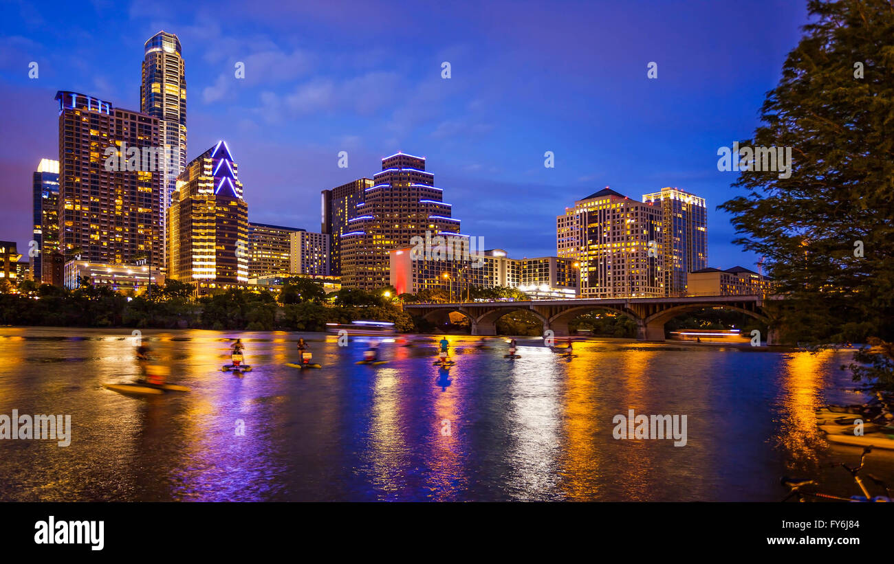 Austin, Texas downtown skyline at night on the Colorado River as unidentified tourists ride water bike's (All recognizable faces Stock Photo