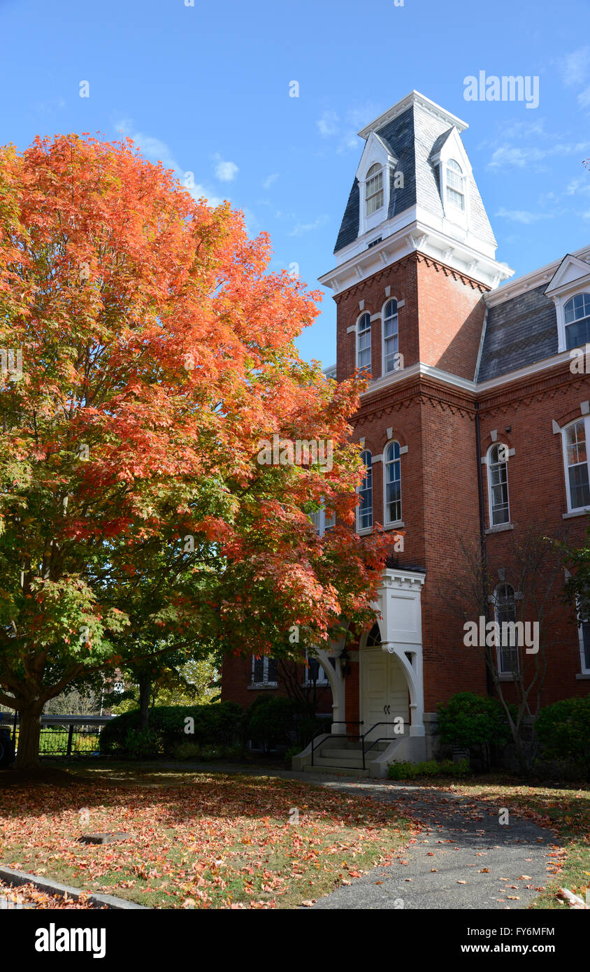 large red brick building in Stonington Connecticut.  There is a large tree by the structure with colorful autumn leaves. Stock Photo