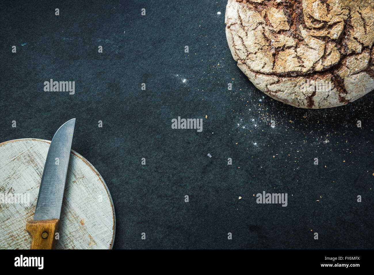 Artisan whole grain rye bread, on dark slate. Ingredients border background Stock Photo