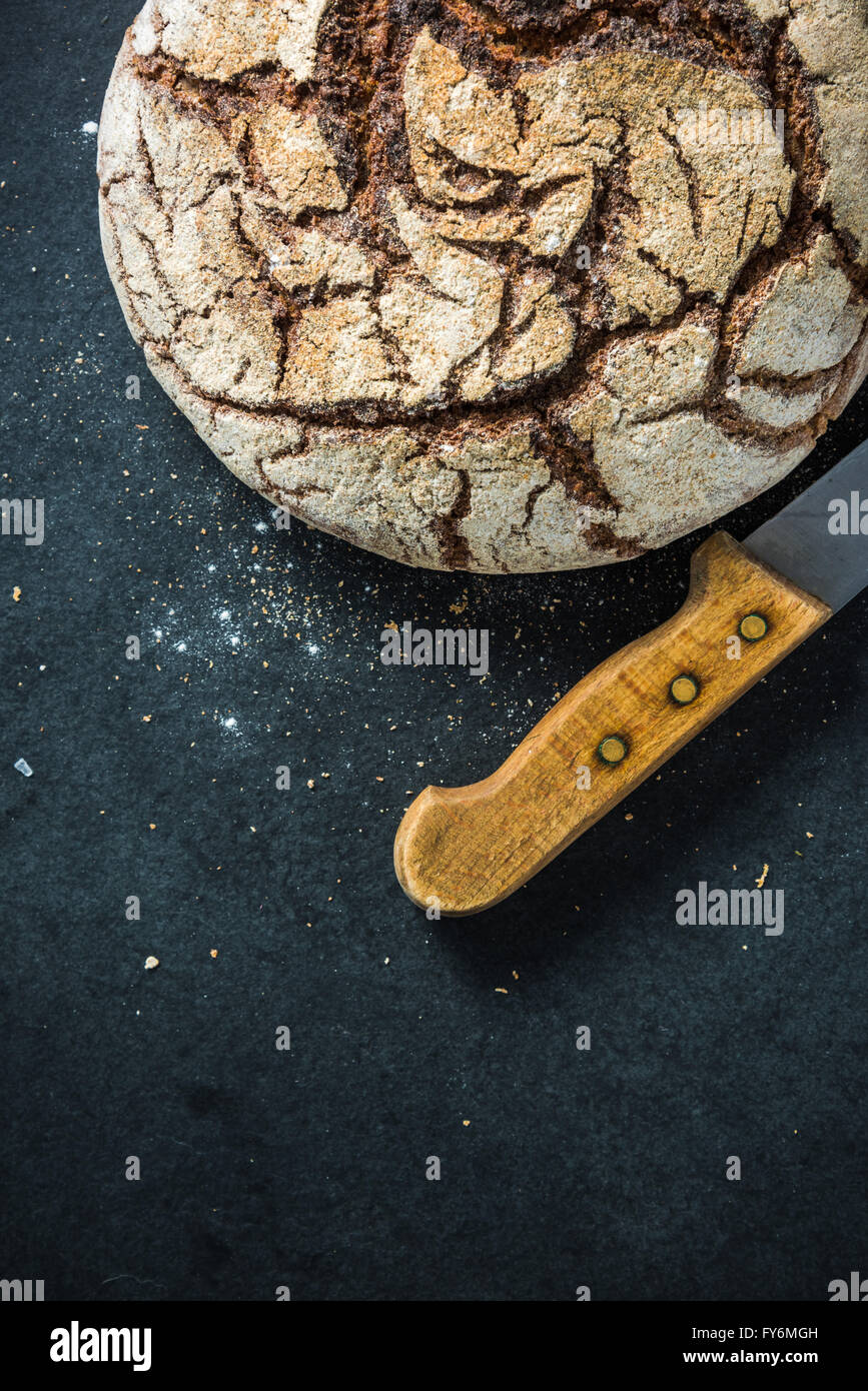 Artisan whole grain rye bread, on dark slate. Ingredients border background Stock Photo