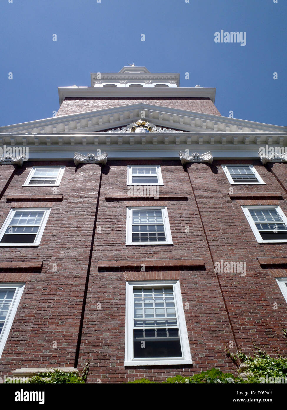Side of Historic Old Red Brick Harvard Building with white framed windows and crown modeling on the accents of the building. Stock Photo