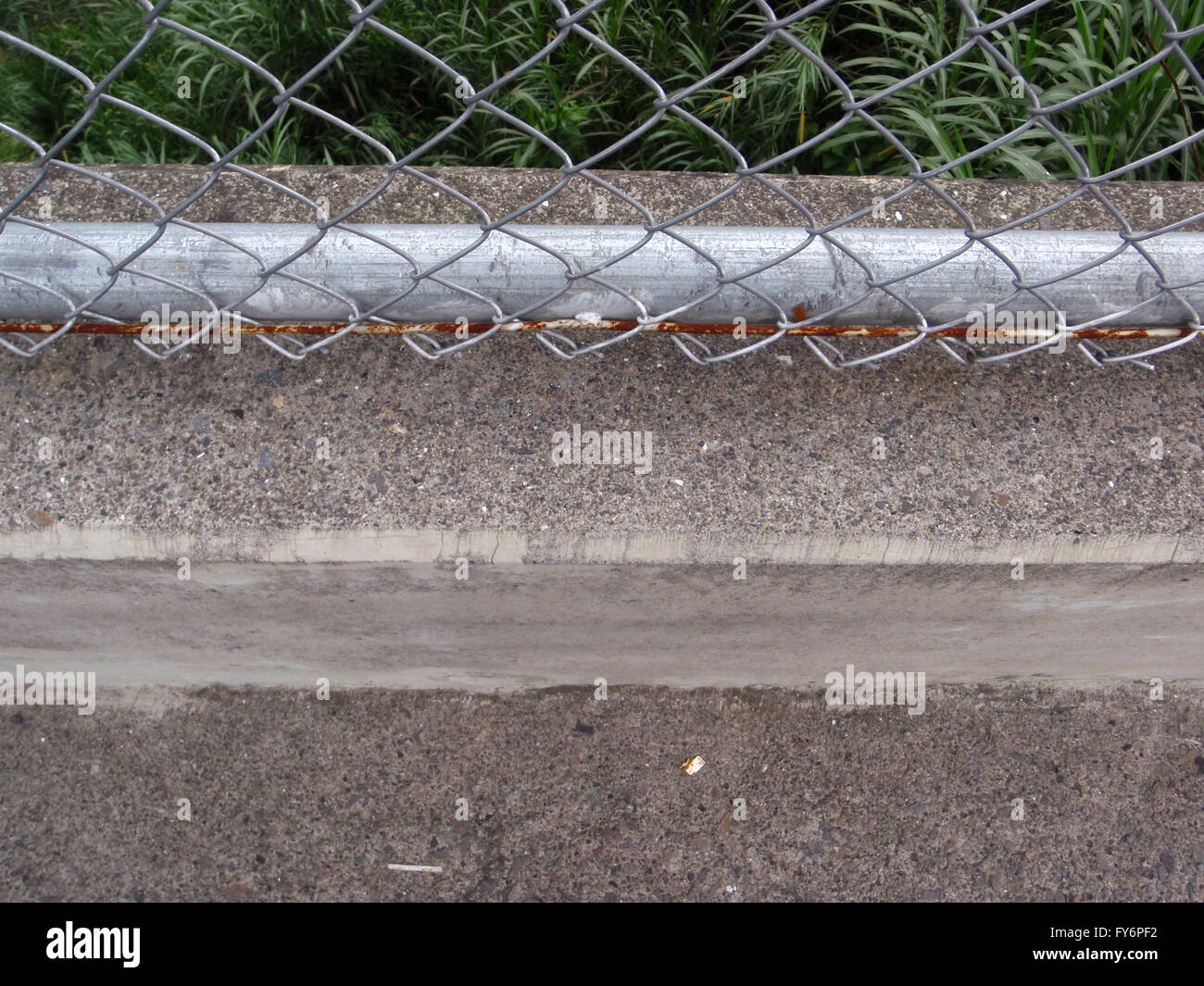 Rusted Chain link fence and concrete sidewalk its attached to and