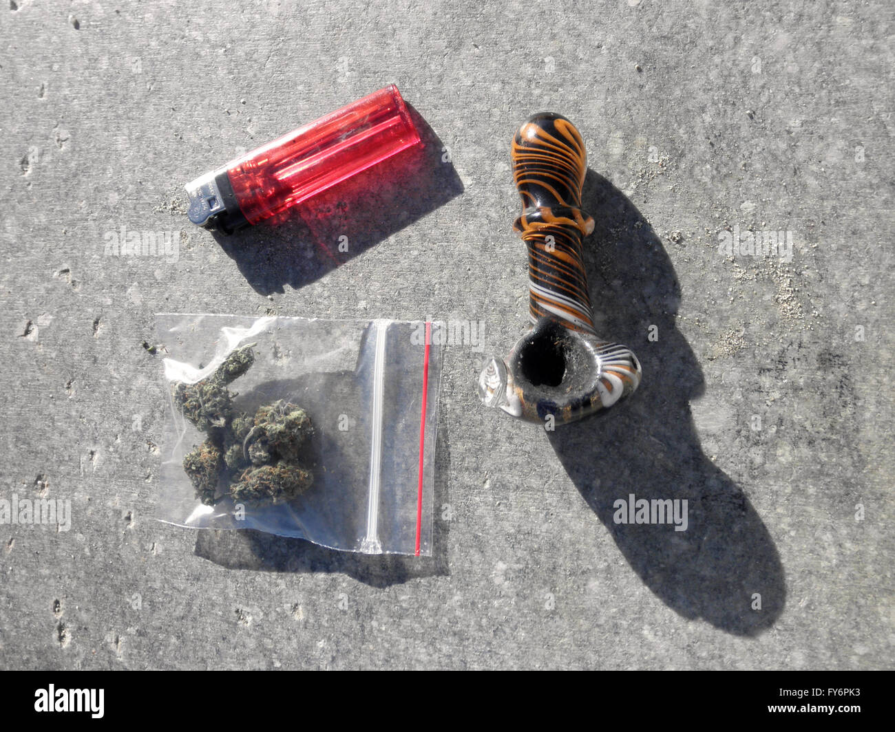 Bag of Medical Marijuana, Pipe and lighter sitting on a concrete slab