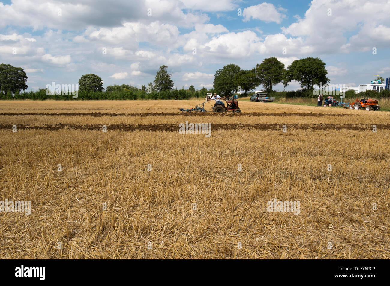 Man driving a small vintage tractor ploughing a field at the Fairford Steam Rally