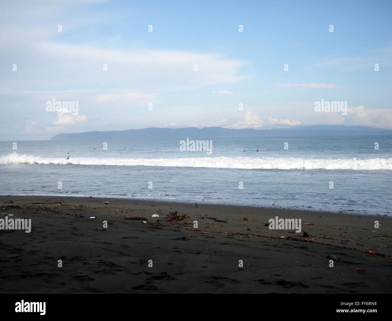 People wait for waves in the surf in Pavones, Costa Rica. Stock Photo