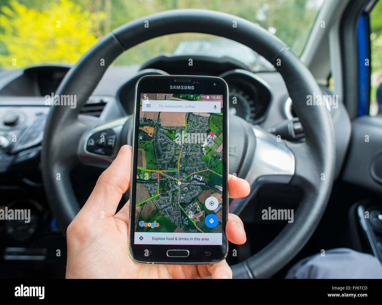 Close-up of a hand holding a phone with the Google Maps app open inside a Ford Fiesta car. Stock Photo