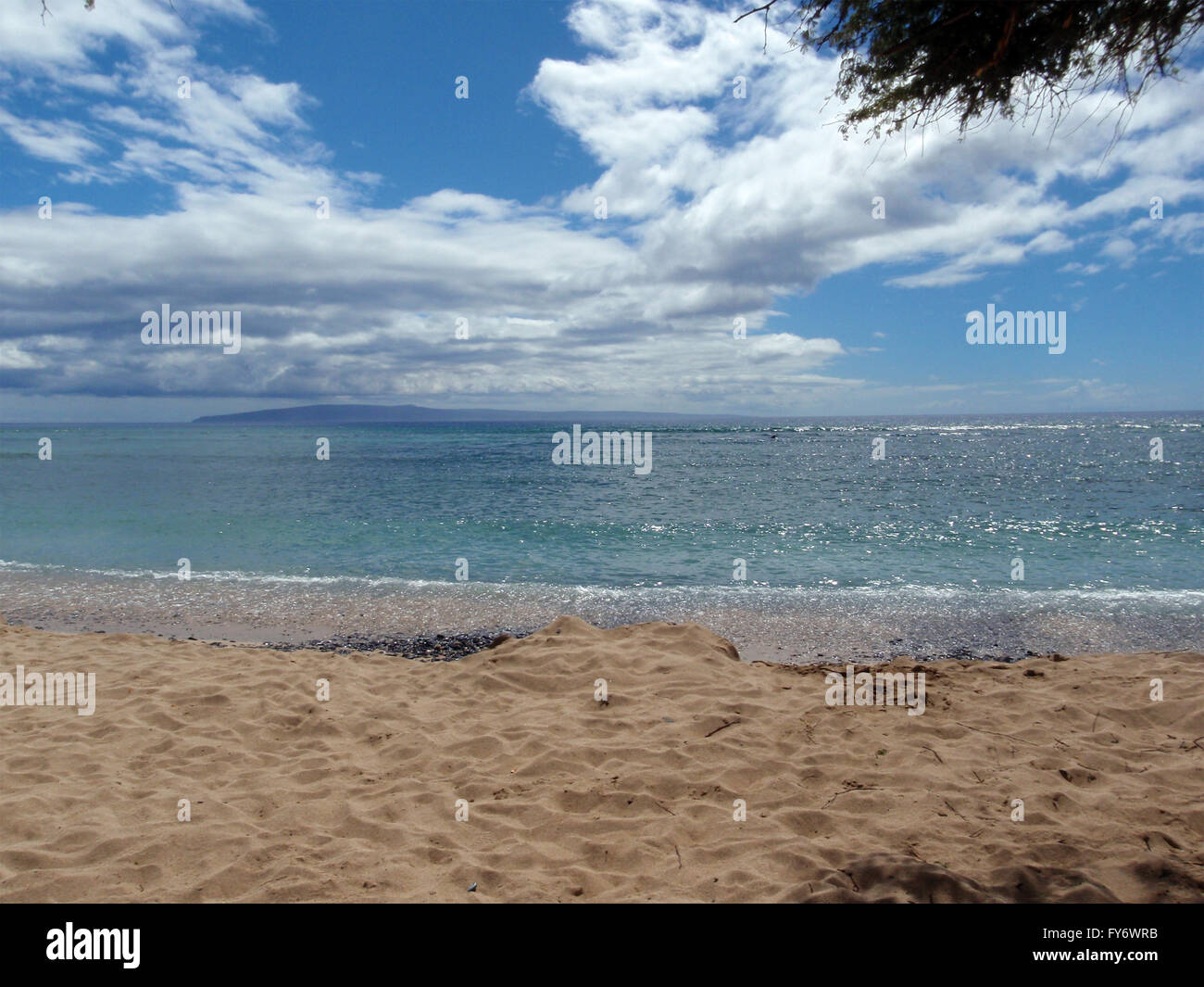 Gentle Waves break on Maui Beach with Molokai visible in the distance