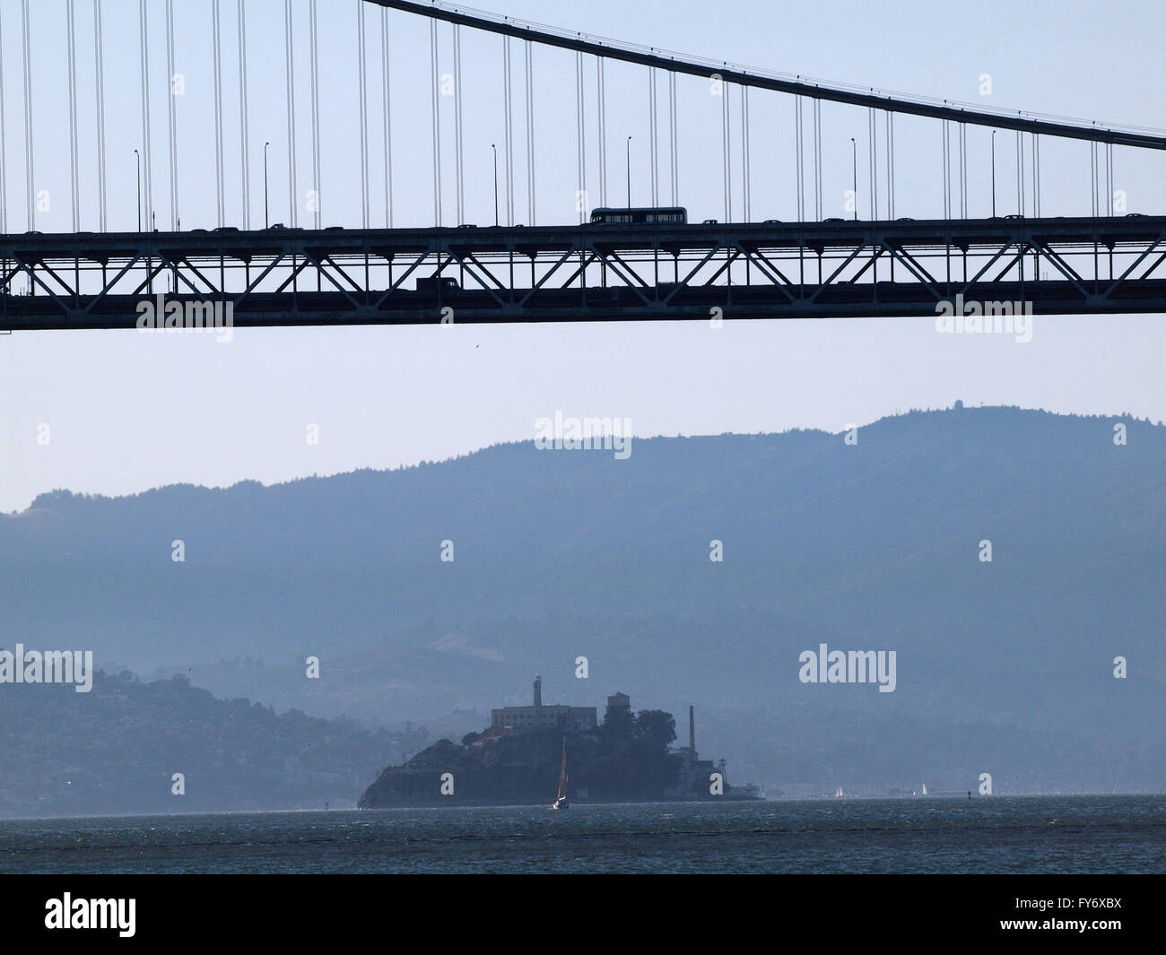 Bay Bridge suspension span with cars and bus driving on it and with Alcatraz Island in the distance underneath , San Francisco Stock Photo