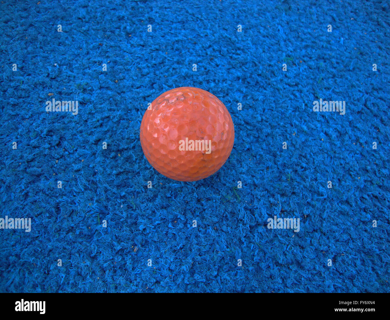 well used Orange golf ball on blue artificial turf Stock Photo