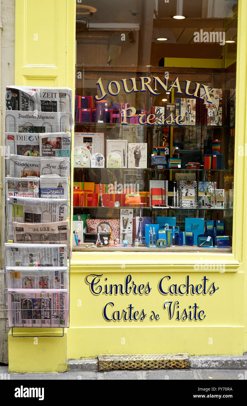 Window of stationery store with newspapers in different languages display beside in Saint