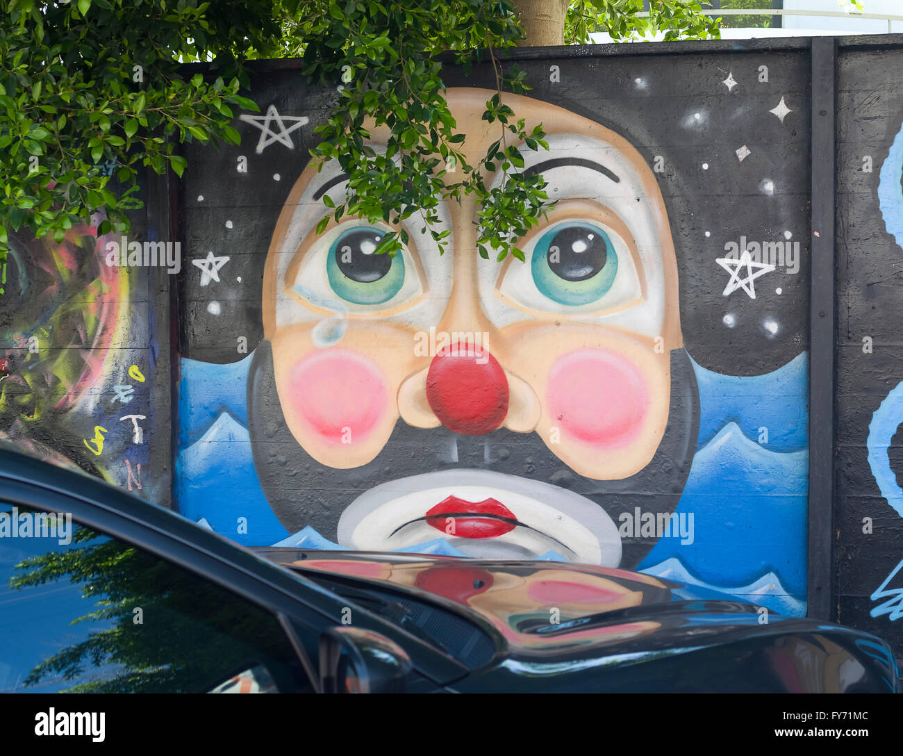A colorful wall mural in a parking lot off of Melrose Ave. in Los Angeles, California depicts a colorful clown face Stock Photo