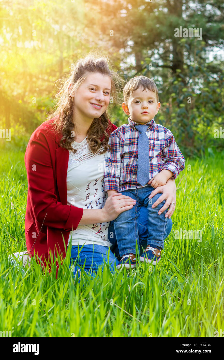 Beautiful pregnant woman outdoor with her little boy looking at camera. Stock Photo