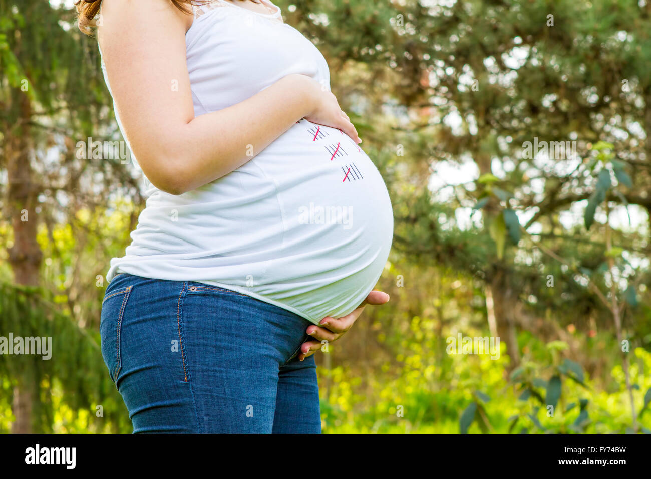 Pregnant young woman outdoors in warm summer day - close up. Stock Photo