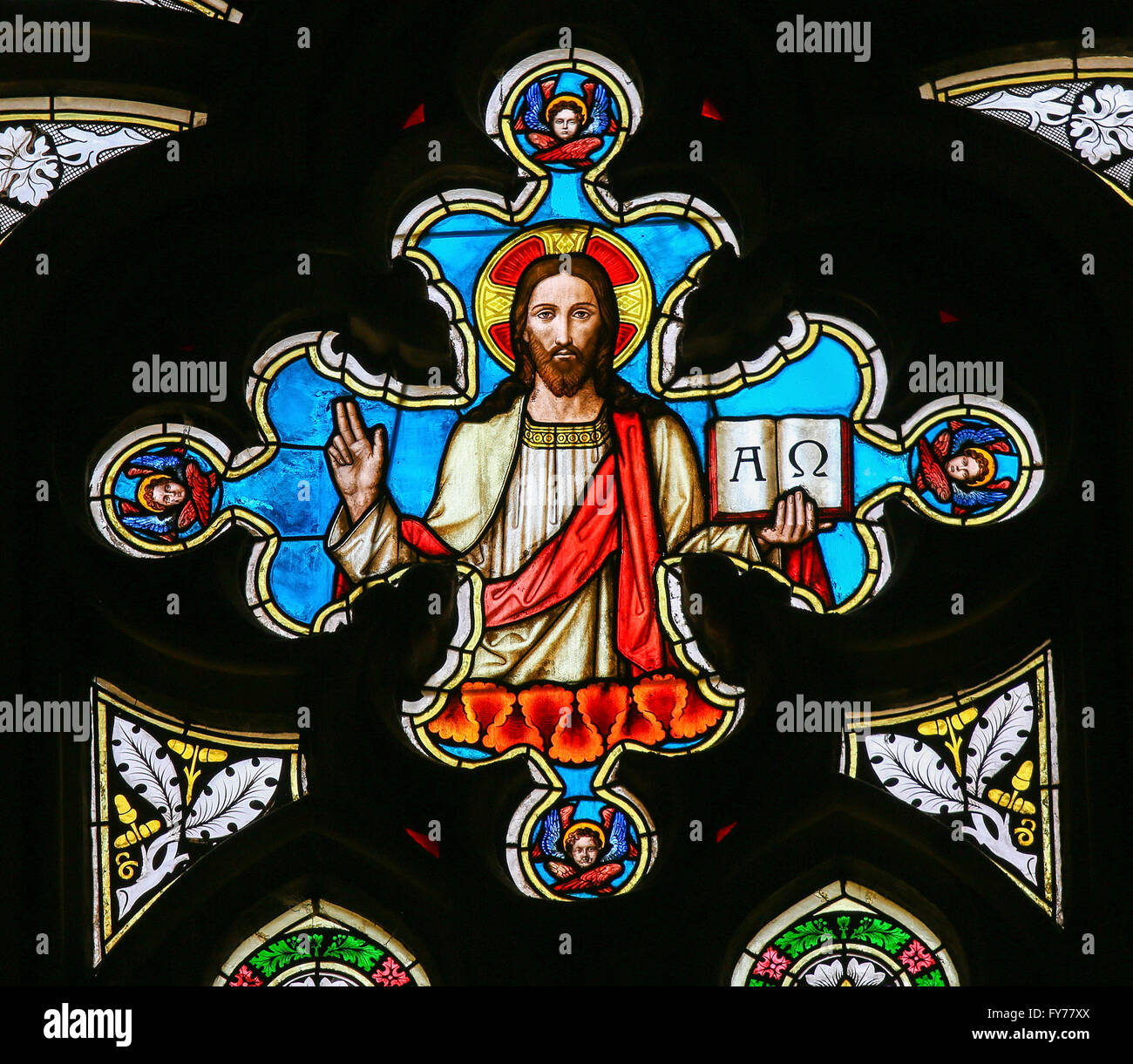 Stained Glass window in St. Vitus Cathedral, Prague, depicting Jesus Christ holding the bible with Greek Letters Alpha and Omega Stock Photo