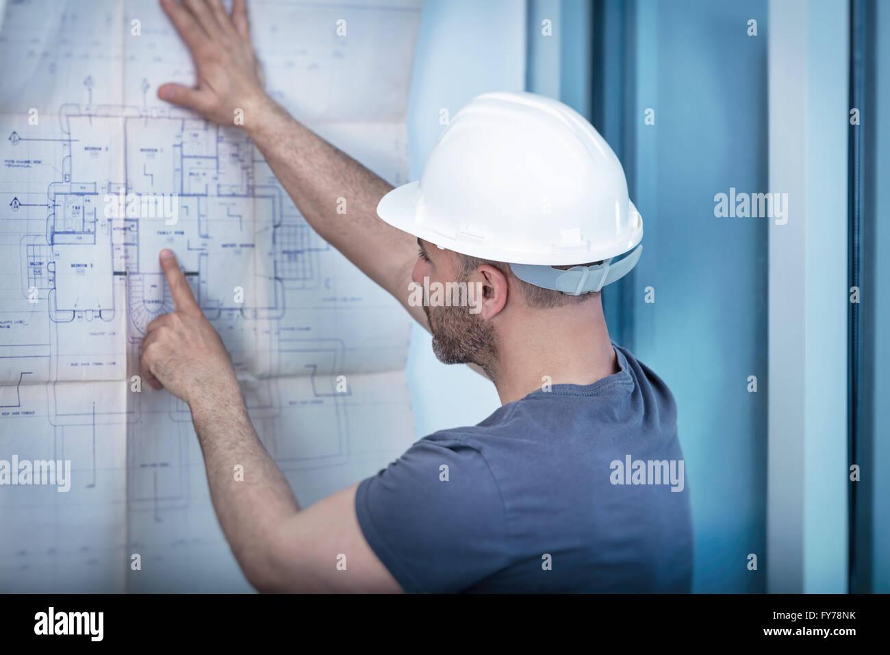 Portrait of an architect builder studying layout plan of the rooms, serious civil engineer working with documents Stock Photo