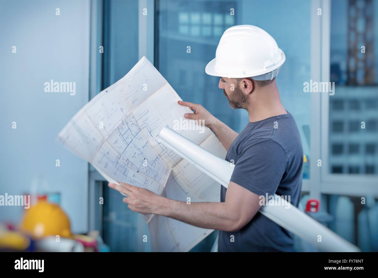 Portrait of an architect builder studying layout plan of the rooms, serious civil engineer working with documents Stock Photo