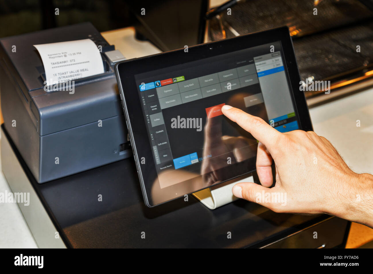POS terminal in coffee cafe waiter's hand when serving customers and touching screen of a tablet with software interface to take Stock Photo