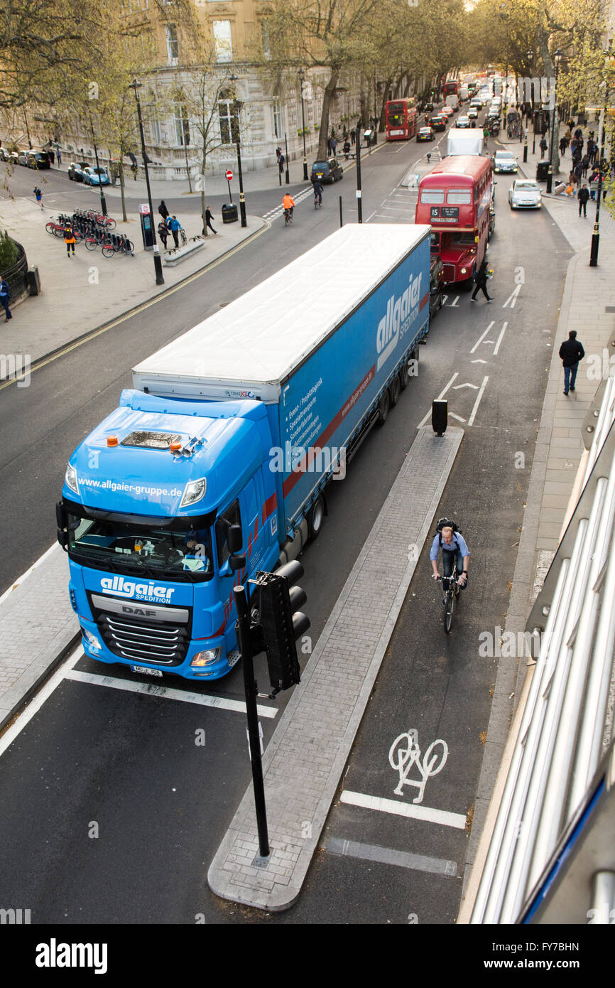 A cyclist is protected from a heavy goods vehicle by the newly built Cycle Superhighway on London's Embankment. Stock Photo