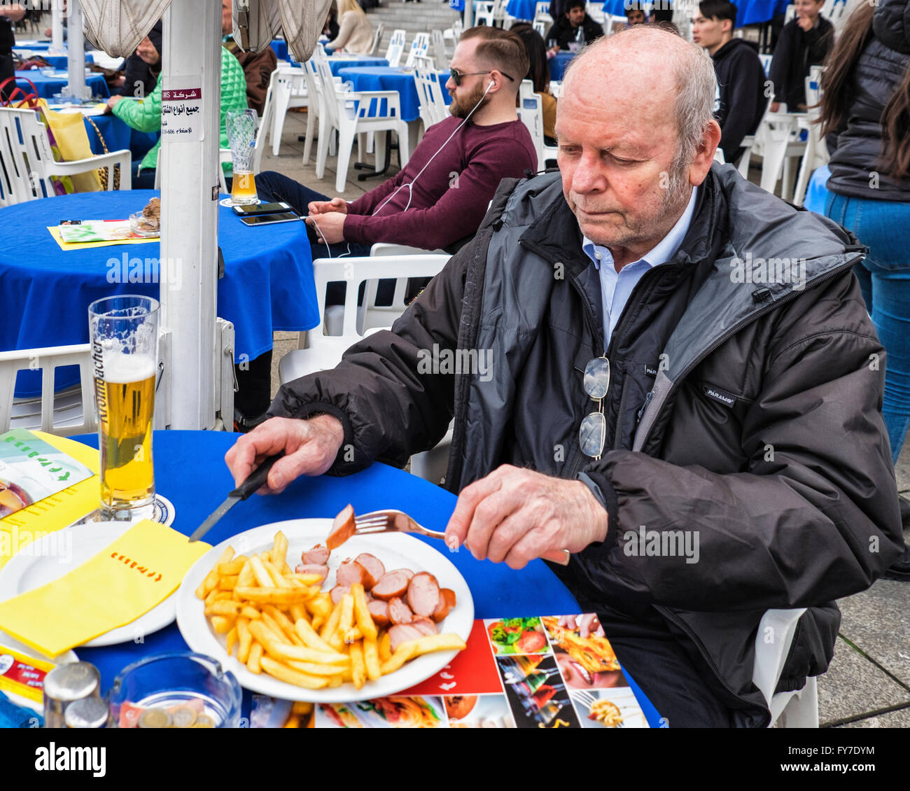 Senior elderly man eating German snack, Bratwurst & chips and beer