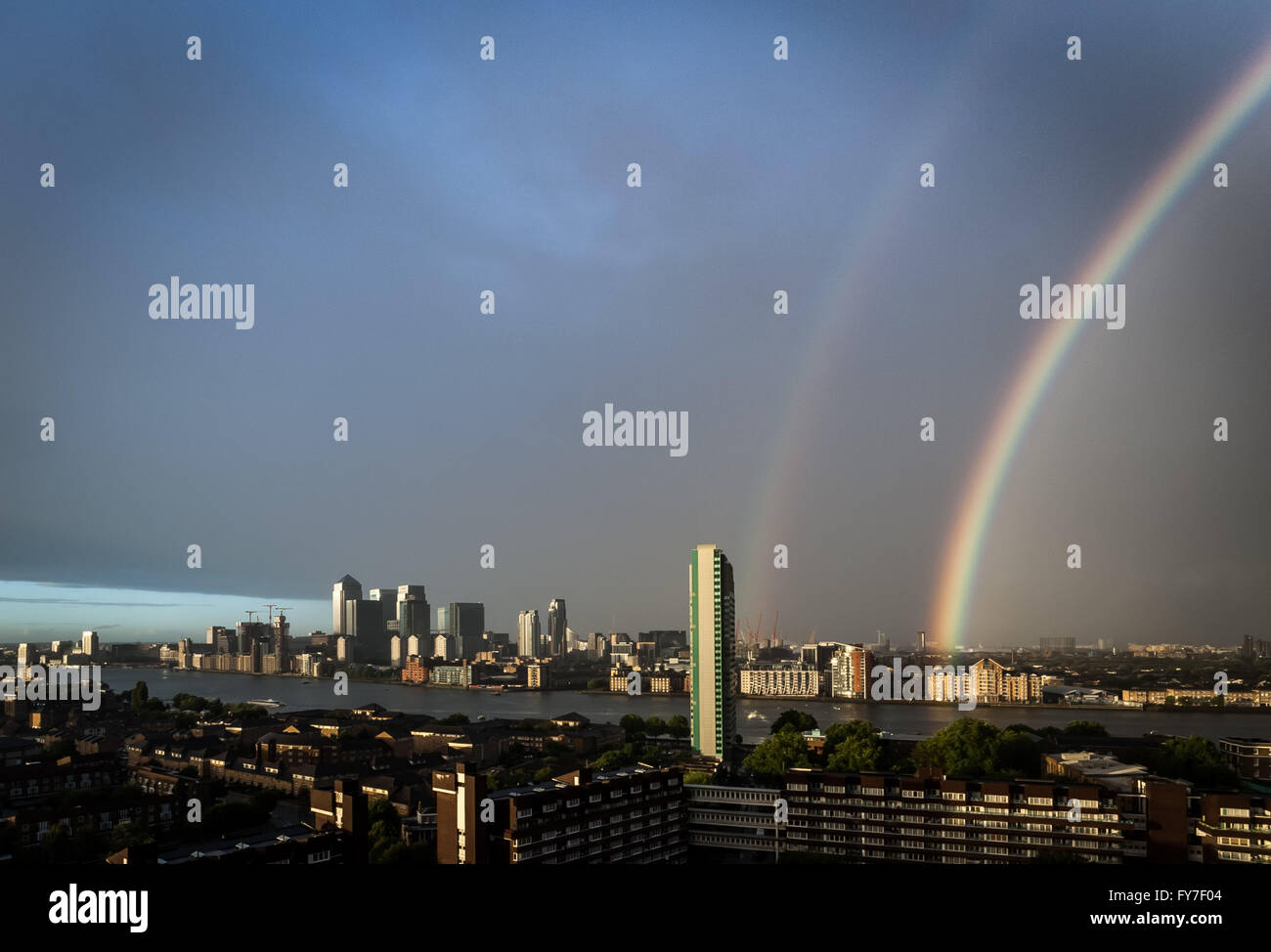 UK Weather: Colourful rainbow breaks after a rainstorm over south east London including Canary Wharf business park buildings Stock Photo