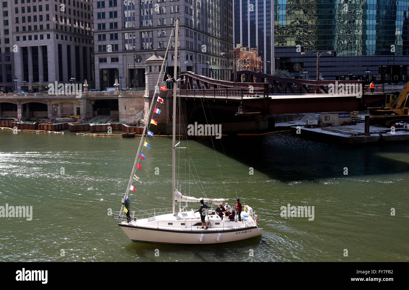 A sailboat makes its way up the Chicago River as a drawbridge is lifted