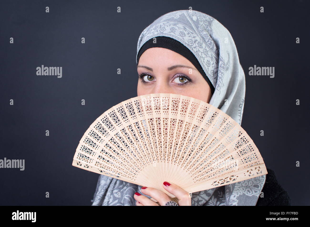Beautiful muslim woman behind a hand fan Stock Photo