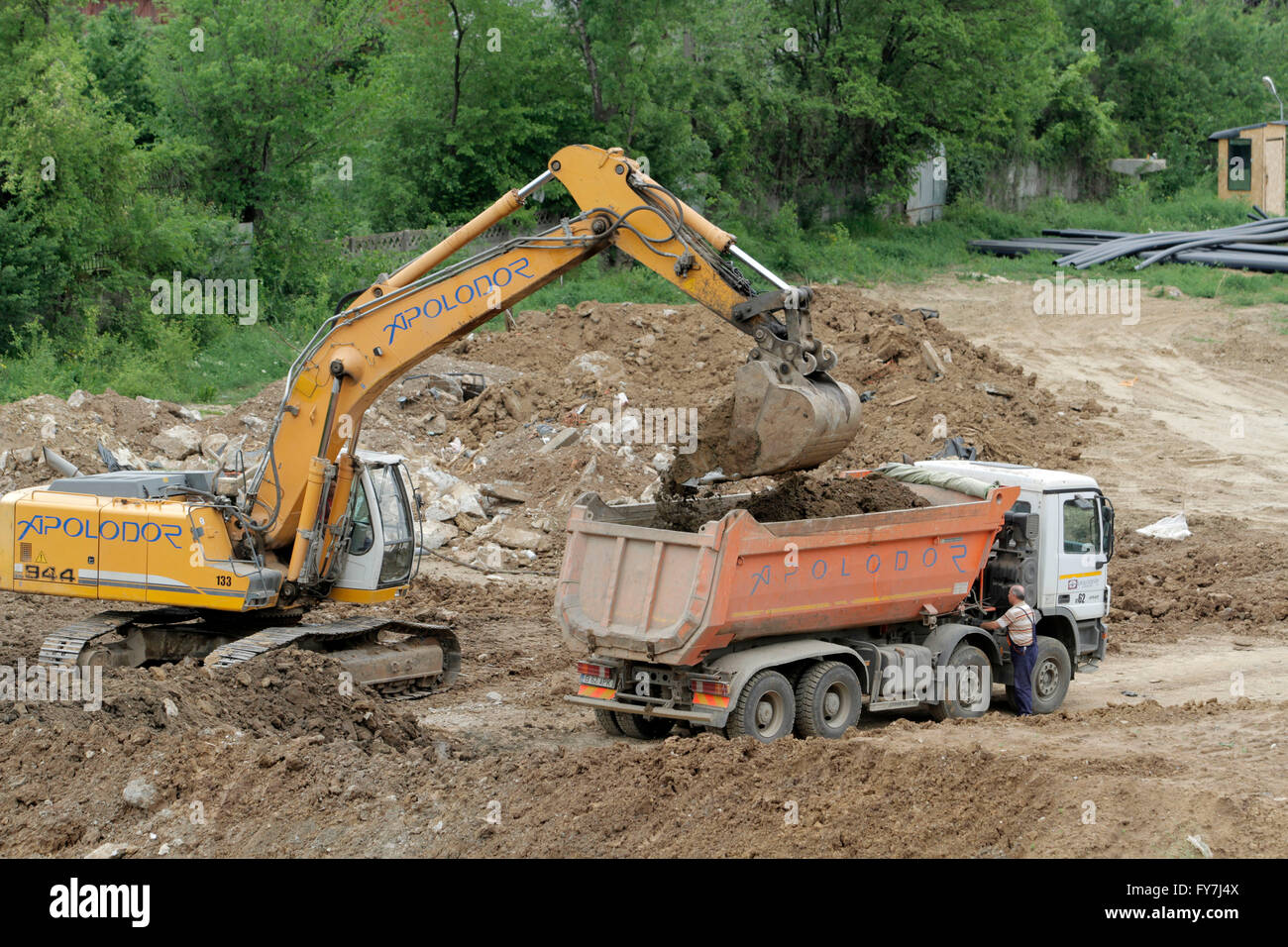Bucharest, Romania, April 19, 2016: An excavator working removing earth and loading it into a truck dumper  on a construction si Stock Photo