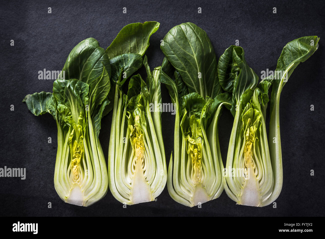 Green chinese cabbage cut in halves on dark slate, vegetable background Stock Photo