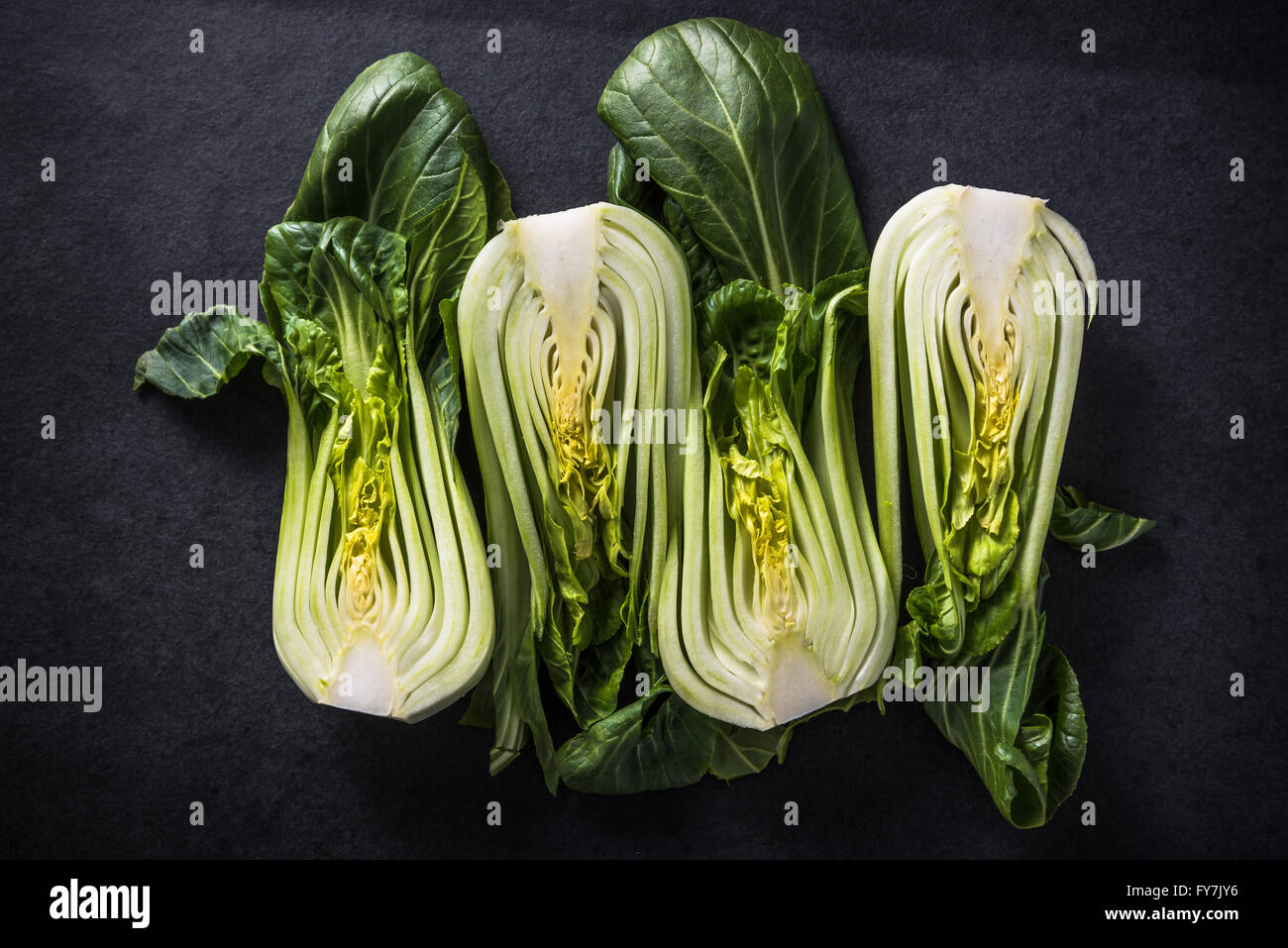 Green chinese cabbage cut in halves on dark slate, vegetable background Stock Photo